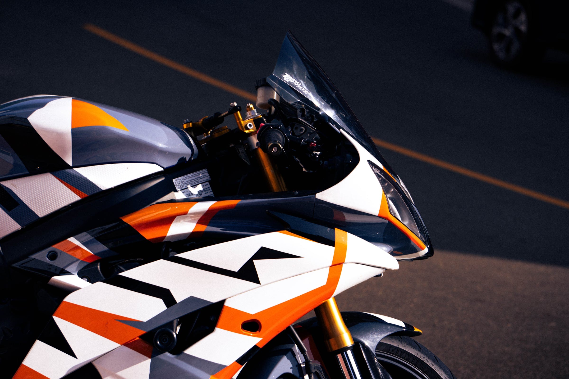 Close view of a sport motorcycle’s white, orange and black geometric fairing.