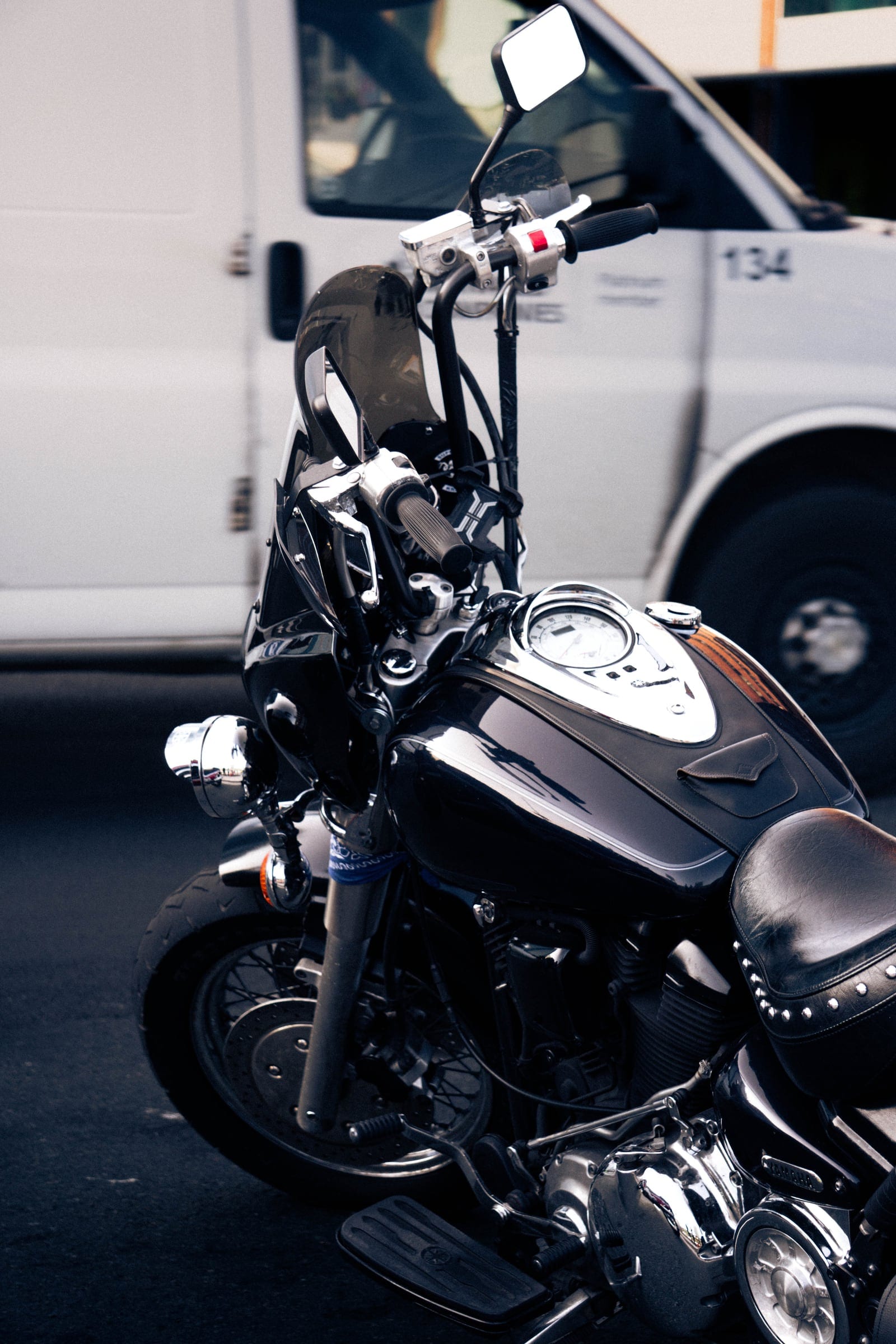 A black cruiser motorcycle with chrome details parked in front of a white van.