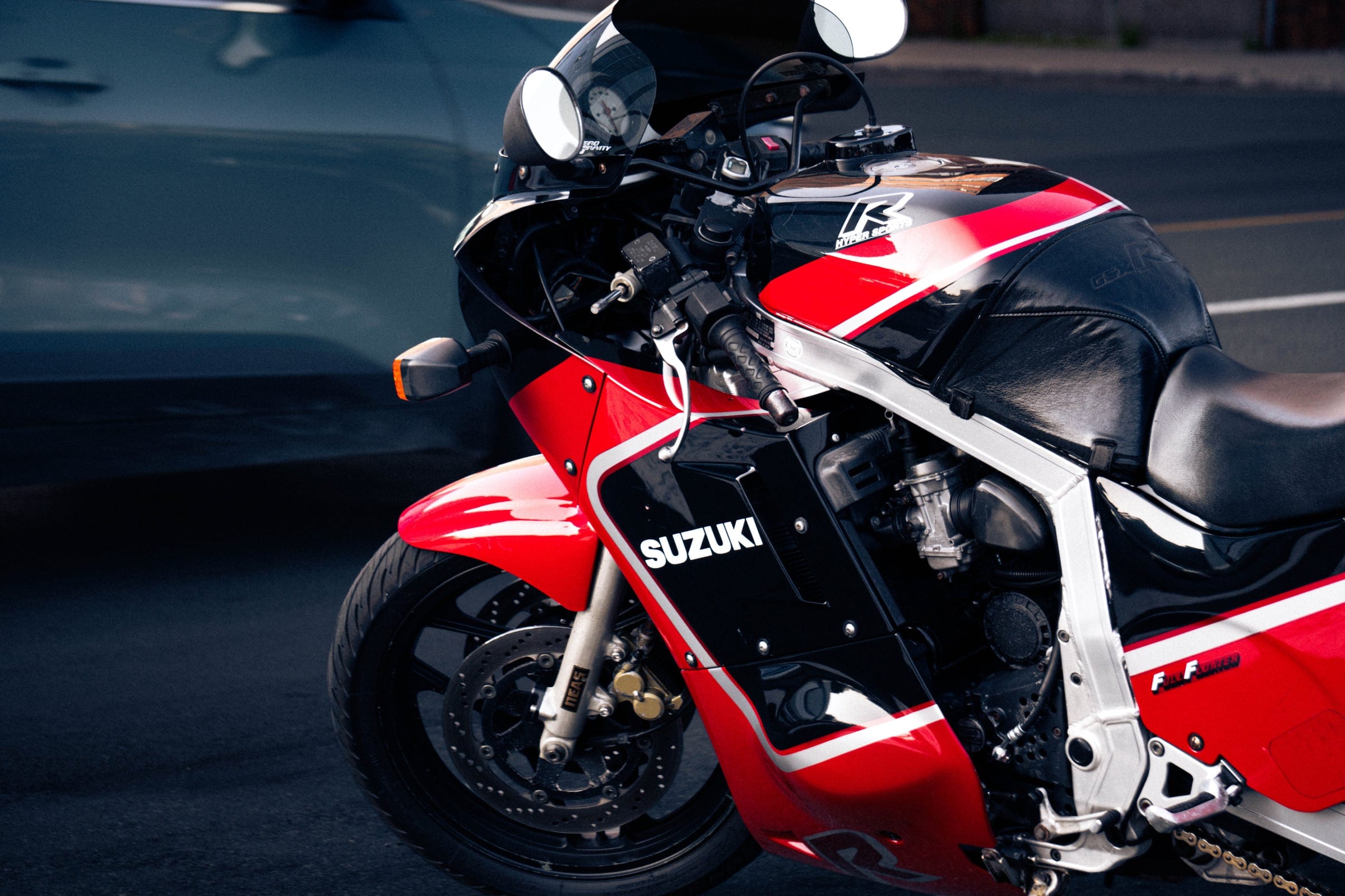 A red, white and black Suzuki GSX-R motorcycle on the street.