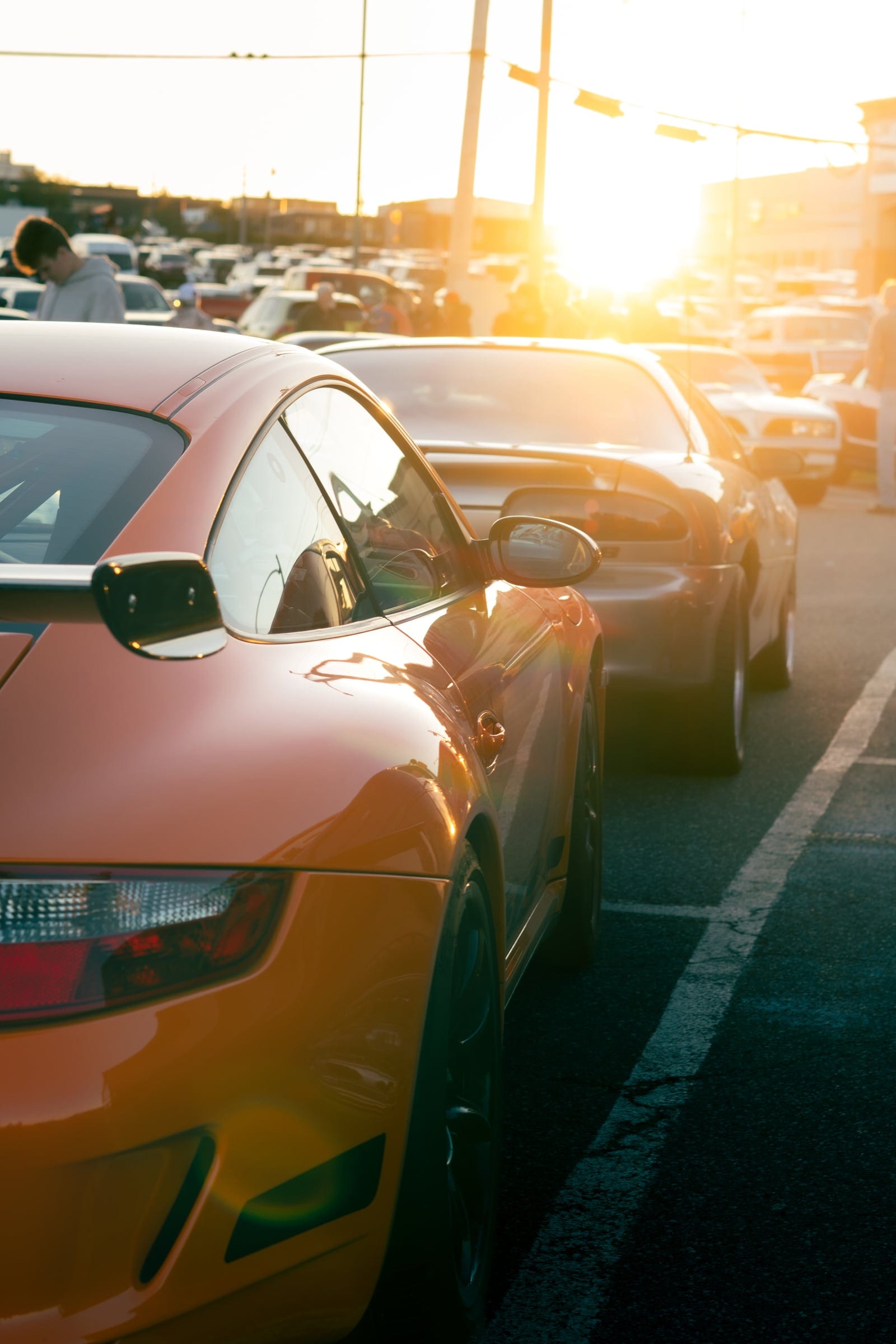 The sun flaring over a line of parked car roofs at the end of the day.