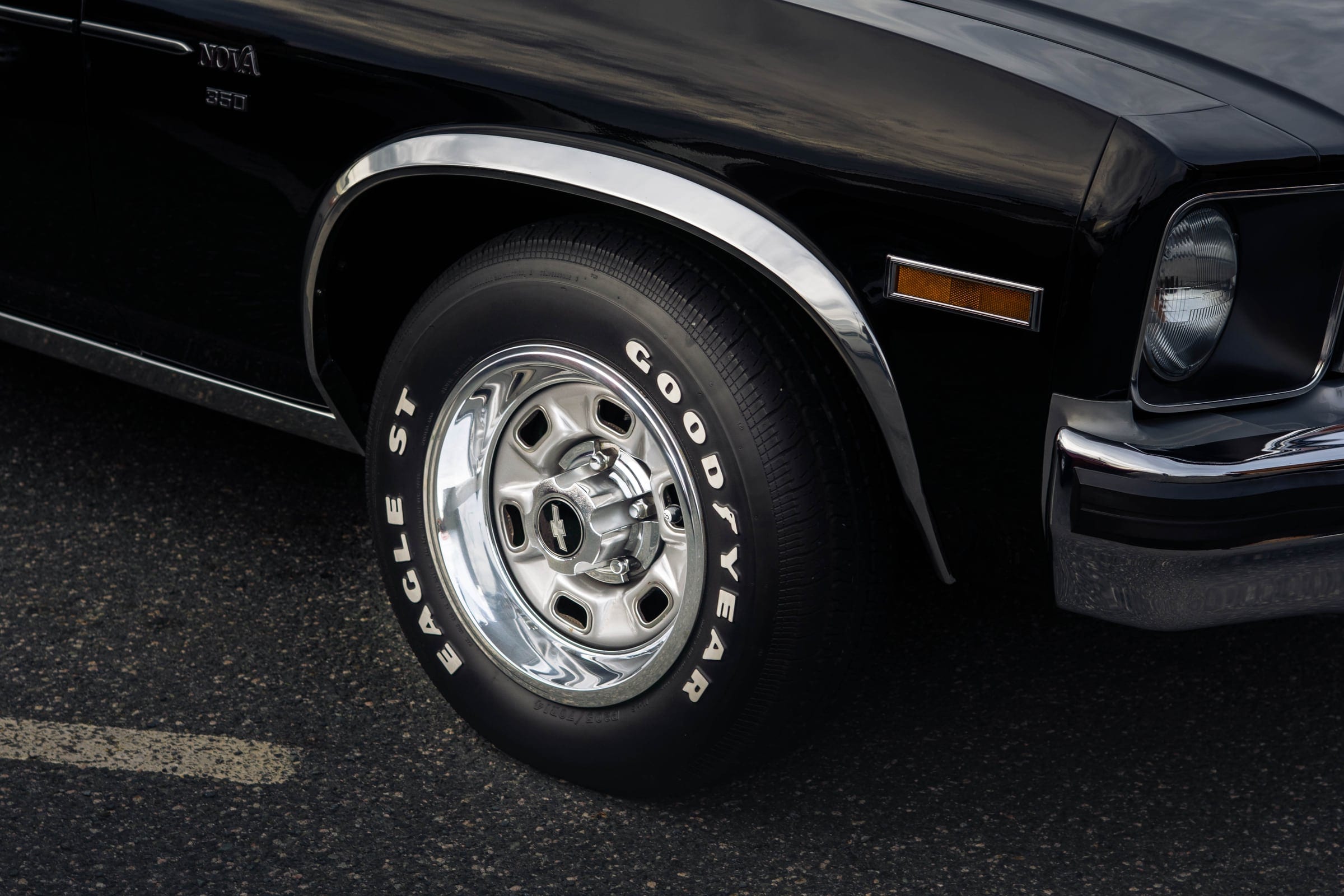 A chrome wheel and raised white lettering on a tyre, close and low.