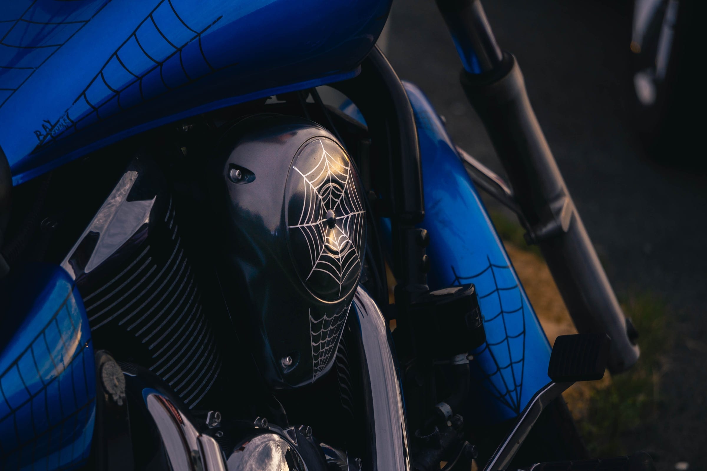 The engine and chrome cover of a blue motorcycle, close.