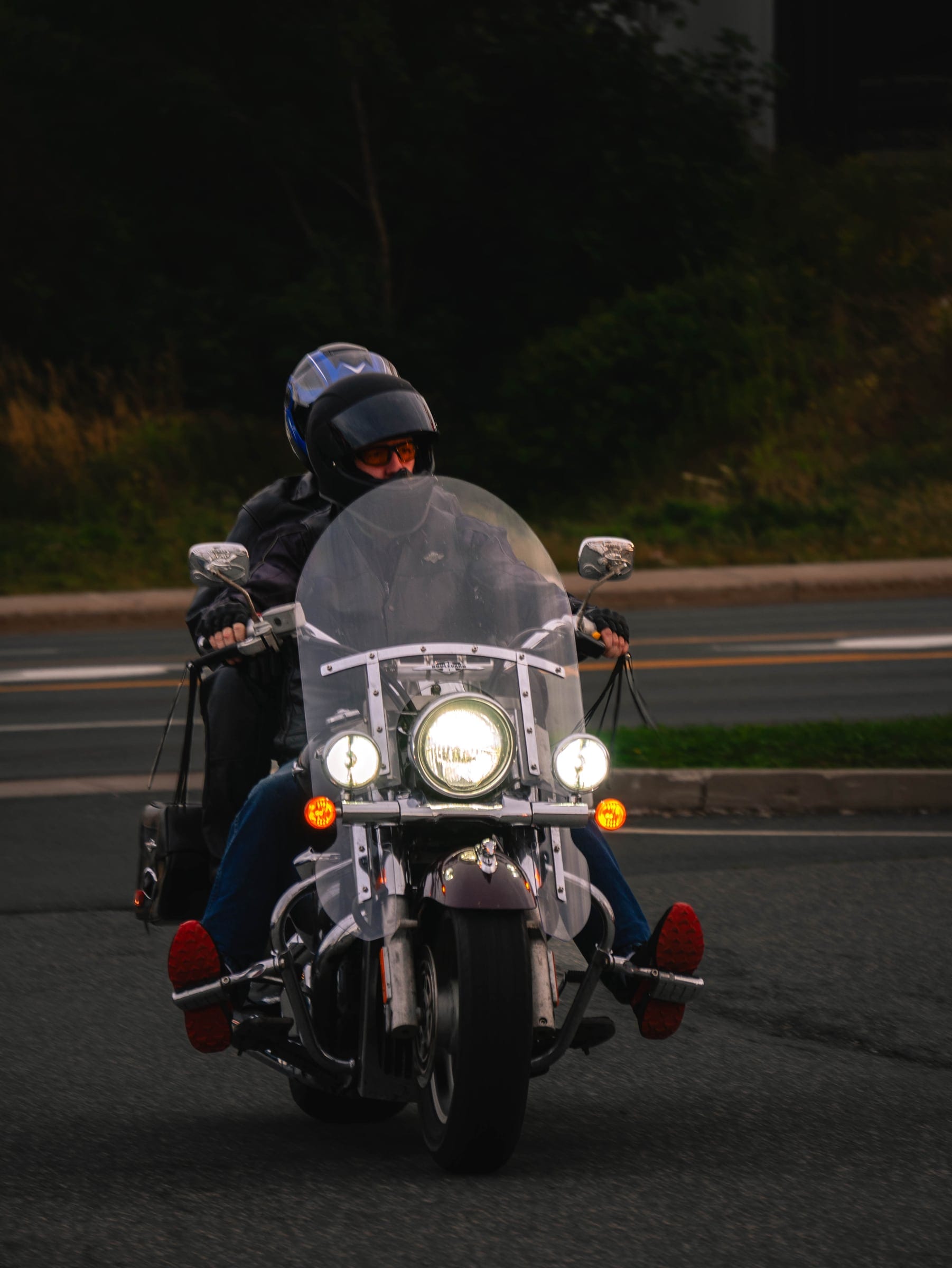 A rider on a cruiser pulling onto the road, headlight on, seen from behind.