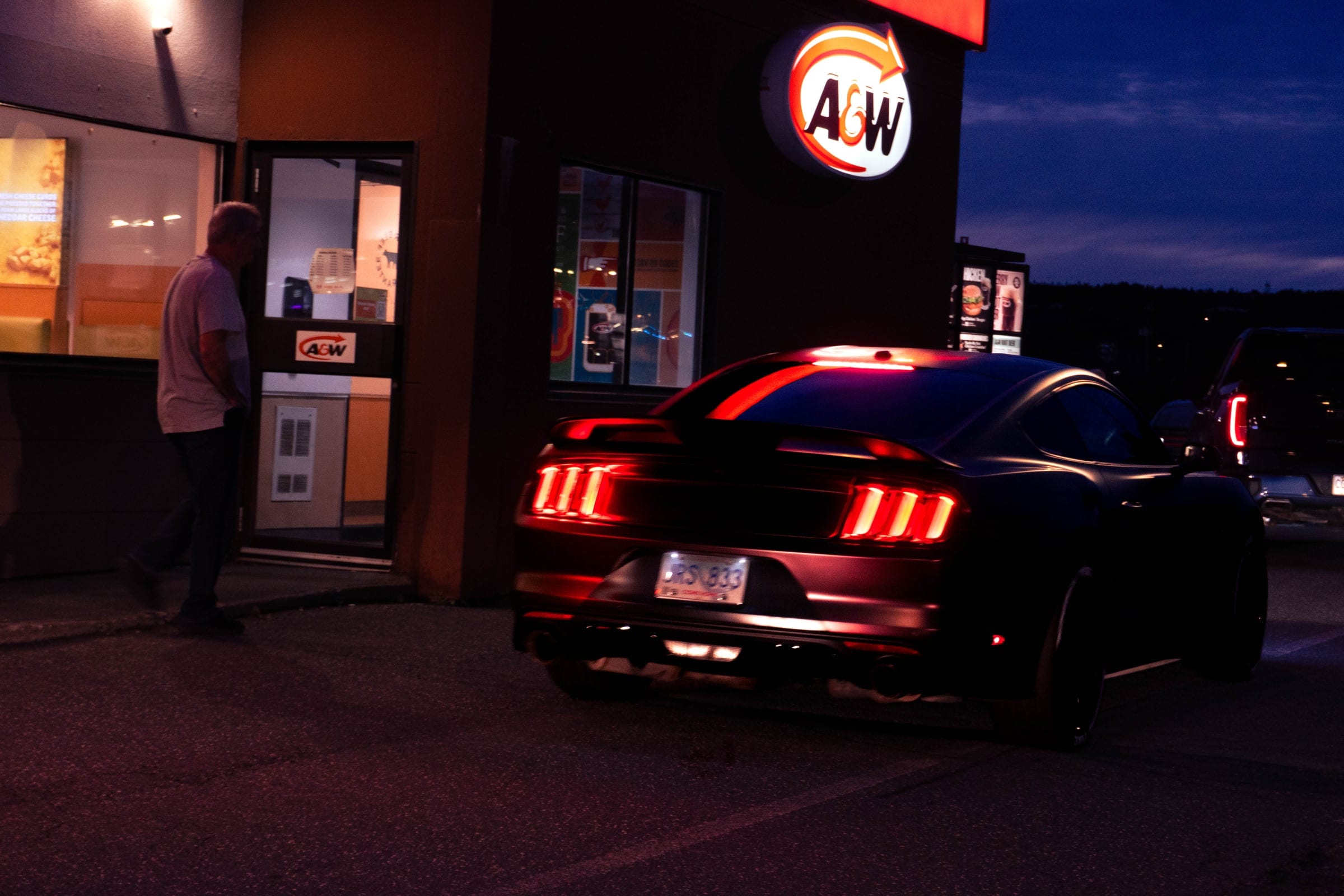 A Mustang’s tail lights lit outside a late-night A&W.